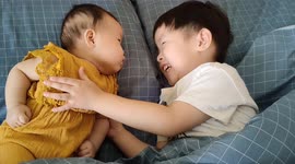Precious moment of little sister and brother lying on bed looking each other