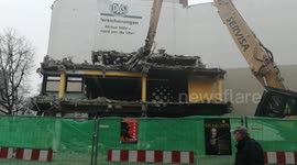 A building is being demolished in Berlin. A huge mechanical arm destroys an old building.