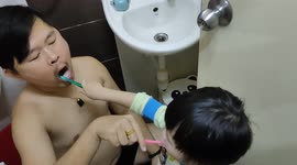 Adorable moment of toddler brushes dad's teeth while dad brushing his teeth at the same time