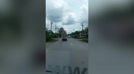 Trash falls from overloaded truck in Thailand