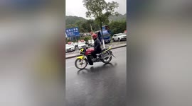 Chinese man casually rides motorcycle with both hands in his pockets