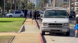 As LAPD Helicopter flys at palm tree and roof top level during Man Hunt on the bluff above Santa Monica Beach — LAPD pulled over a white van and the suspects ran down beach stairs towards the beach.