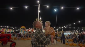 Father tossing daughter into air at a Halloween pumpkin patch