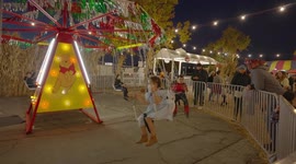 Young boy throws Halloween mask, while on swings at a festival.