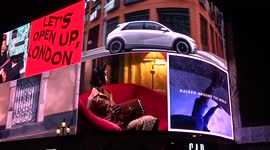 Piccadilly Lights by night with 'Lets open up, London' slogan