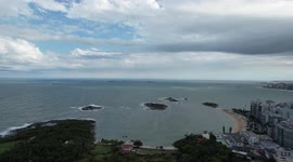 Viewed by drone in a 360 degree swivel. Showing the beach, hill and buildings