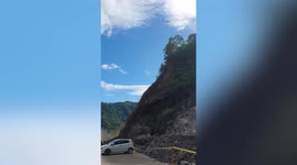 Landslide blocks road while motorists drive after heavy rain in the Philippines