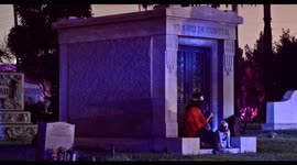 Lady sits by an ancient grave in halloween costume with her dog in the Hollywood Forever Cemetary