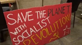 Protesters in a church crypt with 'Save the Planet with Socialist Revolution' placard