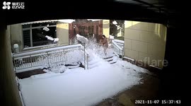 Chinese woman runs away as massive load of snow falls off building