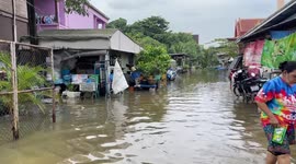Locals wade through flooded streets after Bangkok river overflows following rainstorm