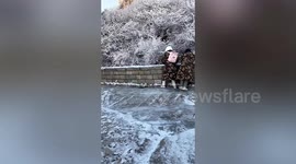 Chinese tourists struggle to walk down icy mountain road due to heavy snow