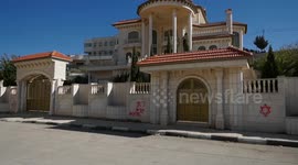 Palestinians inspect vehicles and wall painted with Hebrew following acts of vandalism believed to have been conducted overnight by Israeli settlers