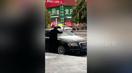 Chinese motorist uses cleaver to remove ice from front windscreen of car