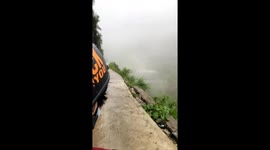 Two men trying to cross the road of death by motorbike in rainy and foggy weather