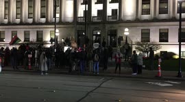 Protesters clash and cause a sign to get thrown into the street and then a group comes to rip it up.