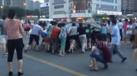 A group of determined women push a parked car out of the way so they can DANCE