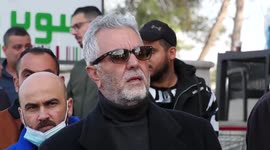 Palestinians hold IDs and banners to demand of the family reunification in the West Bank city of Al-Bireh