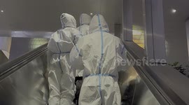 Airline staff walk through LAX's Tom Bradley International Terminal in protective gear amid COVID surge fears