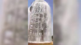 Irrigation tank overflows sending water cascading onto fields below in India
