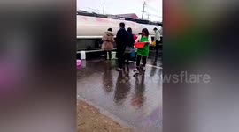 Residents fill containers with petrol after tanker truck flips over in central China