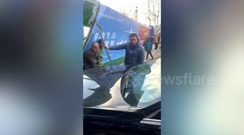 Kind-hearted residents hold up steel frame blown over by strong winds to protect parked car in China