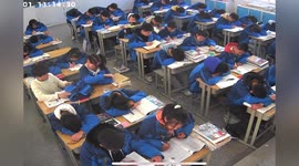 Chinese student takes his jacket off so sleeping deskmate can rest her head