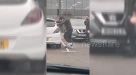 Man vigorously tops up his car tyre air levels with a foot pump in Birmingham, England