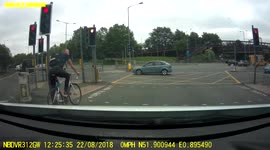 Cyclist ignores red light and almost collides with a car at a busy intersection