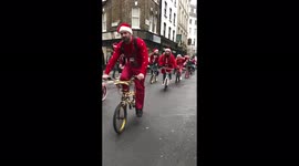 Revellers in Santa costumes ride bicycles through London's Soho