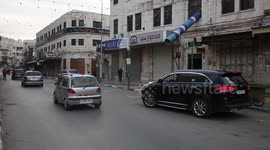 Palestinians walk past shuttered stores in the West Bank city of Nablus