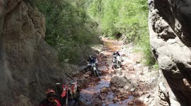 Enduro motorcycles in a wet and permitted area, crossing a river. Aerial with drone