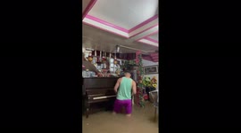 Filipino resident plays piano while standing in knee-deep floodwater brought by Typhoon Rai