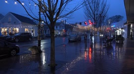 Street with holidays decoration and storefronts with light and traffic on Main street in rainy evening