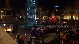 Cheerful carol singing by a choir under Trafalgar Square Christmas tree