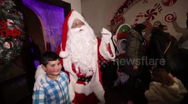 A Palestinian Christian man dressed as Santa Claus dances with children during Christmas celebrations