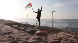 Palestinian artist with amputated leg paints sand sculpture for New Year