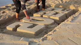 Palestinian youths paint on the sand sculpture