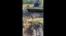The driver used the excavator bucket to move the big boat to the shore professionally