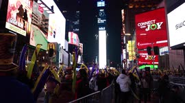 Times Square New Year's Eve revelers dance and wave balloons as midnight approaches