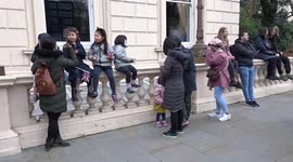 Children with Union Jacks enjoy London New Years Day Parade 2022 performances from Waterloo Place stone balustrades
