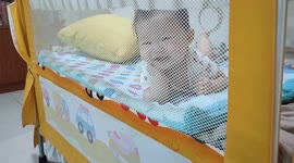 Adorable baby posing like a model in snuggler bed when facing camera