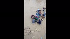 Residents try to save a motorbike in Indonesia's Jayapura after a day of heavy rain causes floods, killing one