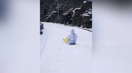 Doctor 'sleds' along snow-covered road on cardboard so he can carry out COVID-19 tests for residents cut off due to weather