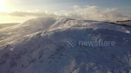 Snow blows across Northern Ireland mountain before sunset in stunning winter scene