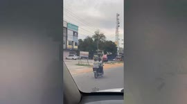 Pillion rider carries huge mirror on moving motorcycle in Indonesia