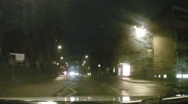 Cyclist pulling wheelies with no lights, in the dark, on wet and rainy night.