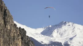 Spectacular daredevil para-skier flight in swiss Alps near steep cliff