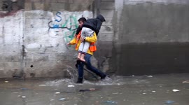 Palestinian child carried to safety from flooded street at Jabalia refugee camp