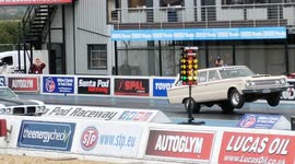 Plymouth station wagon wheelie at Santa Pod drag strip, United Kingdom. Pontiac Firebird in the right lane